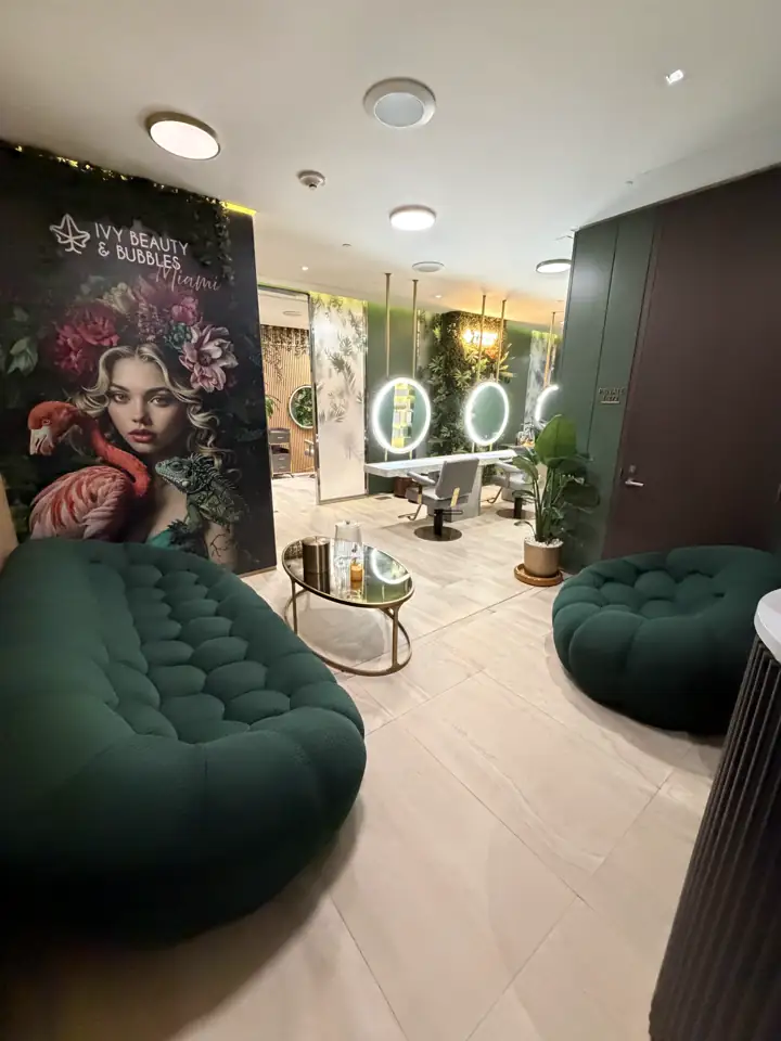 Lobby of IVY Beauty & Bubbles hair salon at The St. Regis Bal Harbour, Miami Beach, with green velvet sofas and lit mirror styling stations